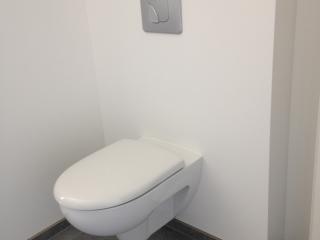Pose d'un WC suspendu dans une salle de bain blanche et grise